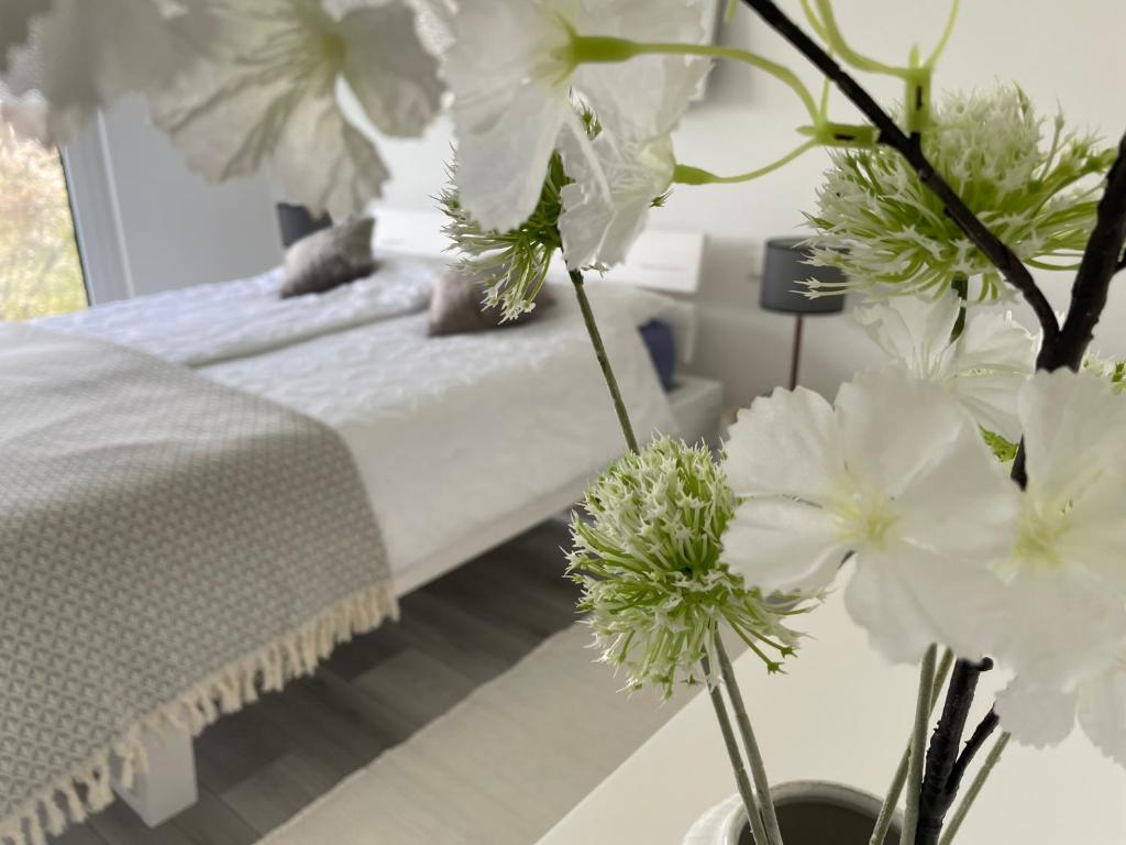 ein Schlafzimmer mit einem Bett mit weißen Blumen in einer Vase in der Unterkunft Apartment mit Stil in Stuttgart