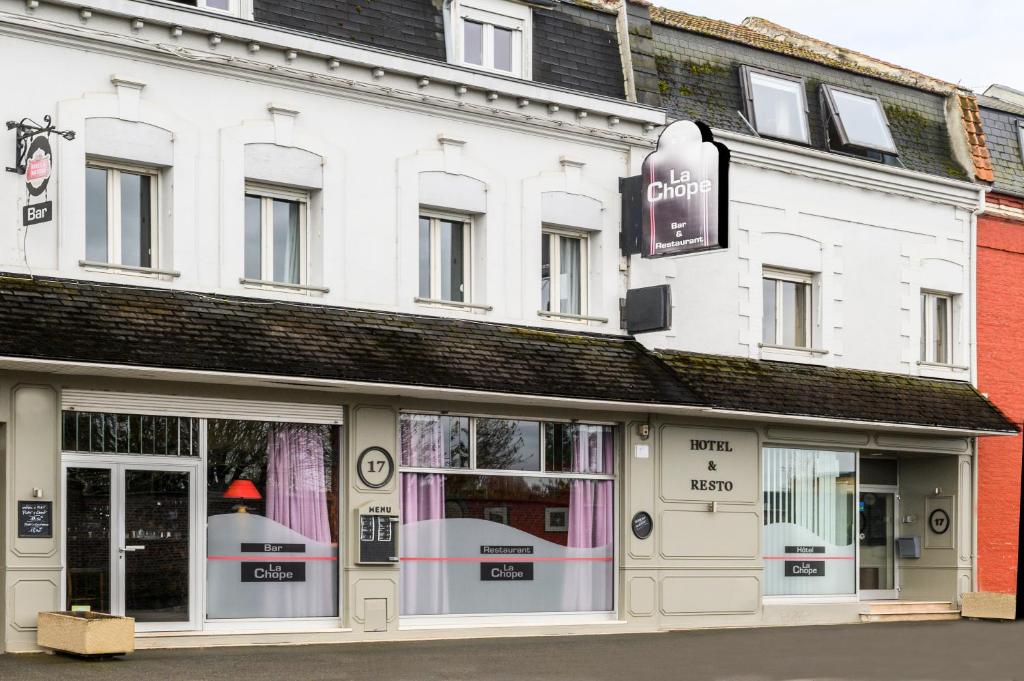 a white building with a sign for a store at Hotel La Chope in Cambrai