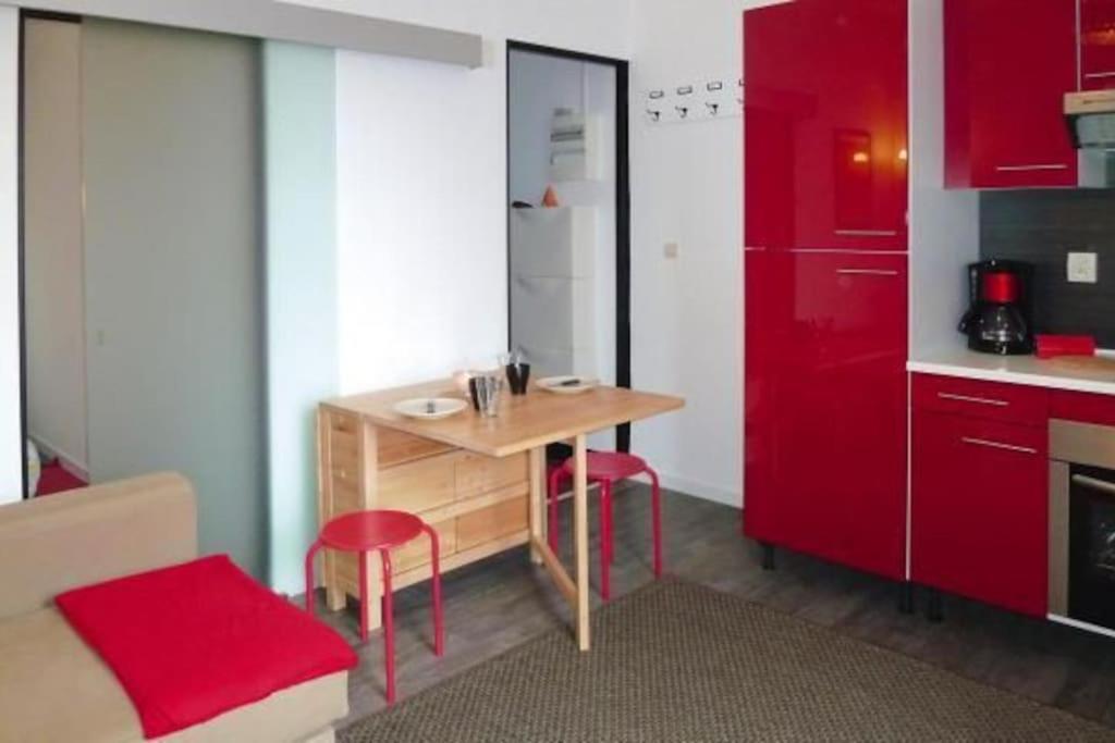 una cucina con tavolo in legno e armadietti rossi di Nid douillet pour 2.. à 50 mètres de la plage a Mers-les-Bains
