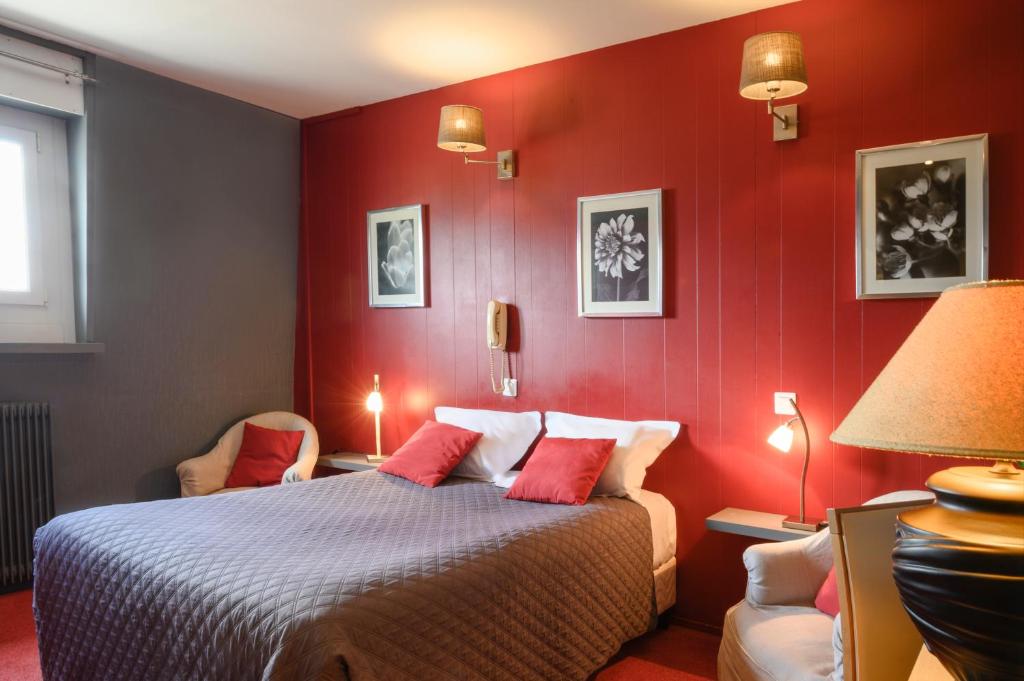 a bedroom with red walls and a bed with two chairs at Hotel La Chope in Cambrai