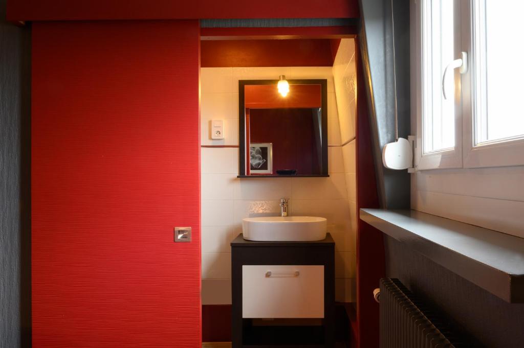 a bathroom with a sink and a red door at Hotel La Chope in Cambrai