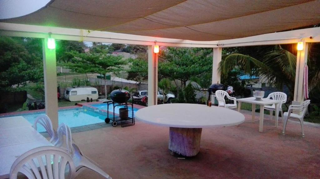 eine Terrasse mit einem Tisch, Stühlen und einem Pool in der Unterkunft Ruis Place in Vila Praia Do Bilene