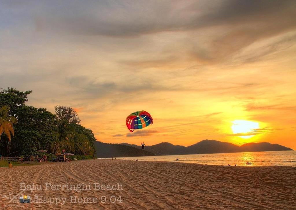 Happy Home 26 Sri Sayang Batu Ferringhi في باتو فيرينغي: شخص يطير طائرة ورقية على الشاطئ عند غروب الشمس
