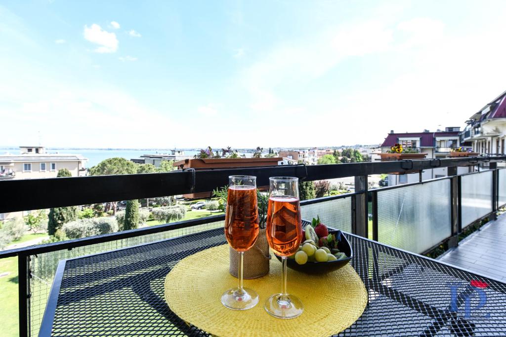 Splendido Apartment DesenzanoLoft Official Partner Homes & Villas by Marriott Bonvoy في ديسينسانو ديل غاردا: كأسين من الشمبانيا على طاولة في الشرفة