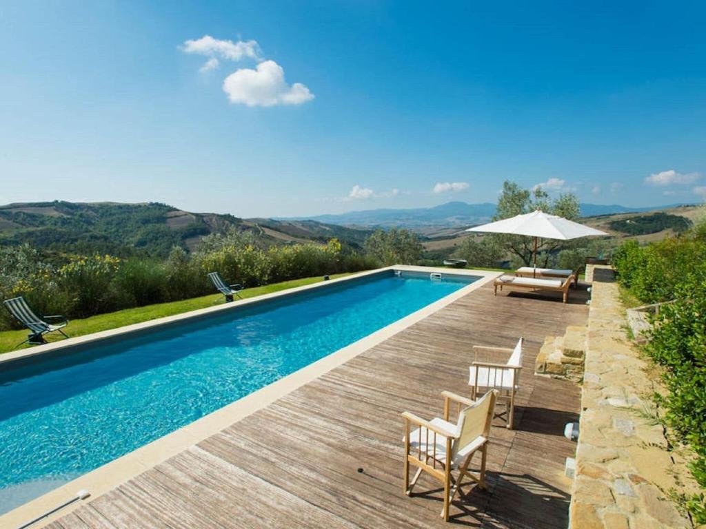 uma piscina com um deque e cadeiras de madeira e um guarda-sol em Belvilla by OYO Villa with private pool em San Casciano dei Bagni