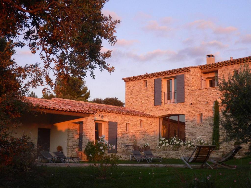 an old brick house with people sitting on chairs in the yard at Superb air-conditioned house with heated pool in Gordes - by feelluxuryholydays in Gordes