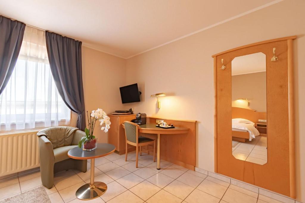 a hotel room with a table and a mirror at Hotel Re'ser Stuff in Roeser