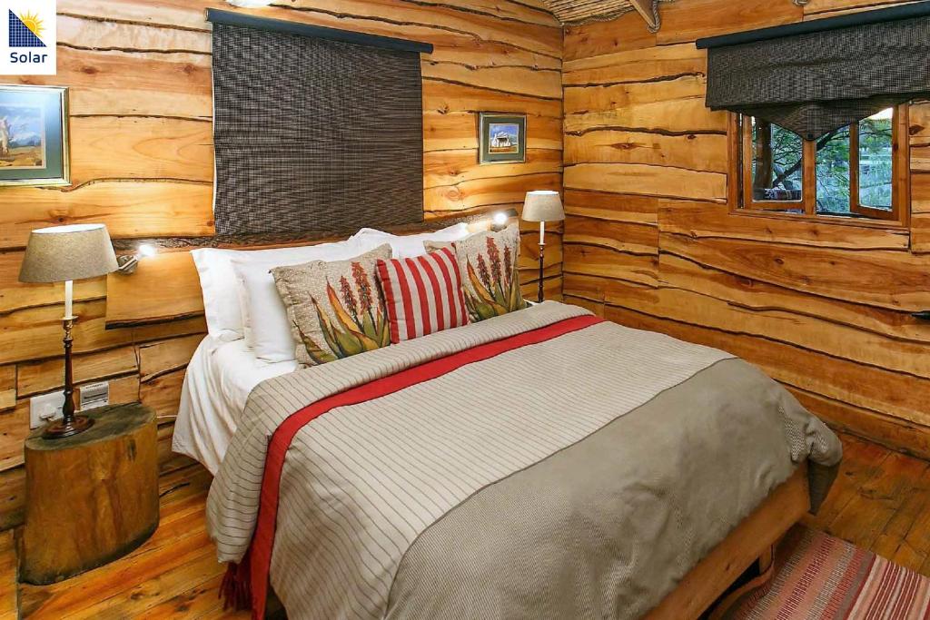a bedroom with a bed in a log cabin at Riverside Guest Lodge in Oudtshoorn