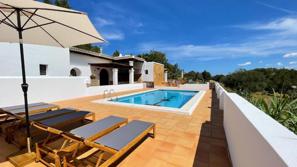 a pool on a deck with chairs and an umbrella at Finca Can Toni den Real in Sant Josep de sa Talaia
