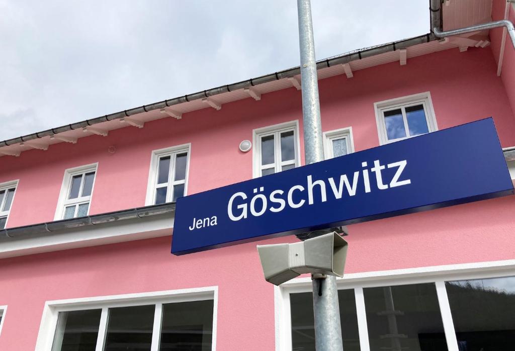 un panneau bleu devant un bâtiment rose dans l'établissement Hotel Gleis 3viertel Jena, à Iéna