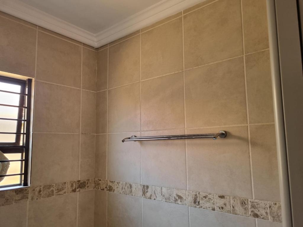 een betegelde douche met een handdoekenrek in de badkamer bij Sunny Estate in Katlehong