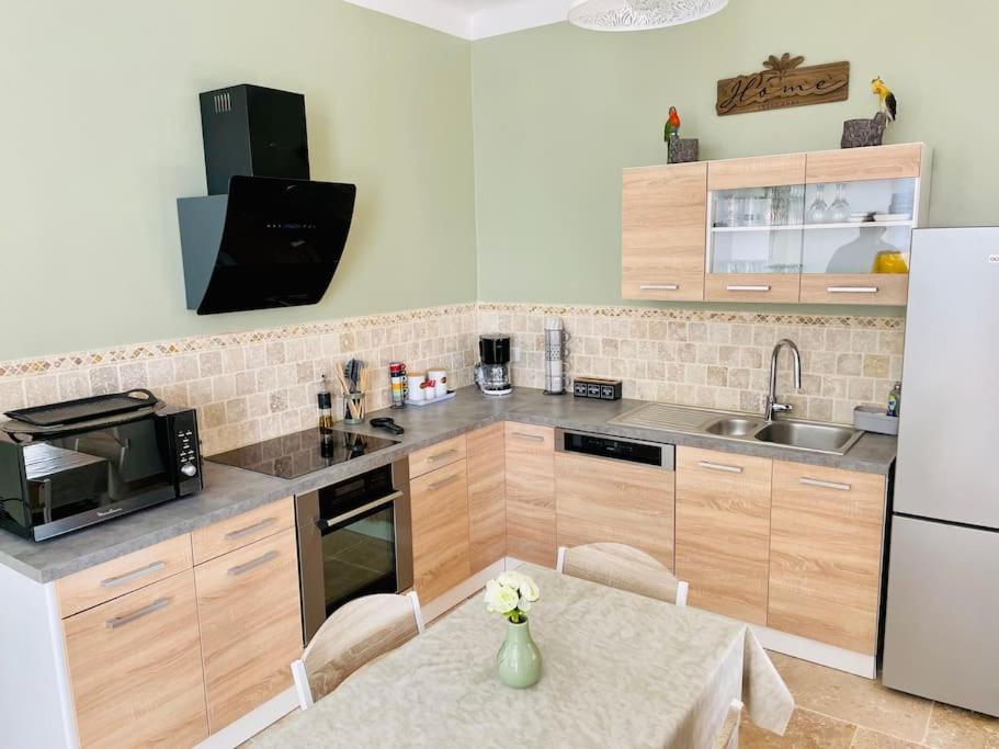 kuchnia ze stołem i białą lodówką w obiekcie Appartement L’olivier w mieście Draguignan