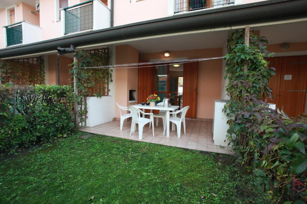 a patio with a table and chairs in front of a house at Terraced house with garden and porch in Rosolina Mare