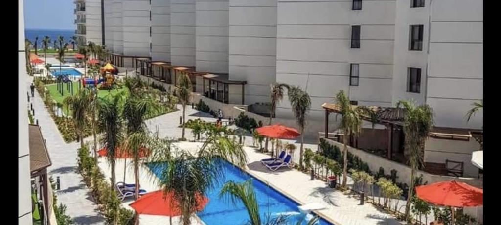 a hotel with a pool and umbrellas and a building at Porto Said Resort Rentals in El-Garâb`a