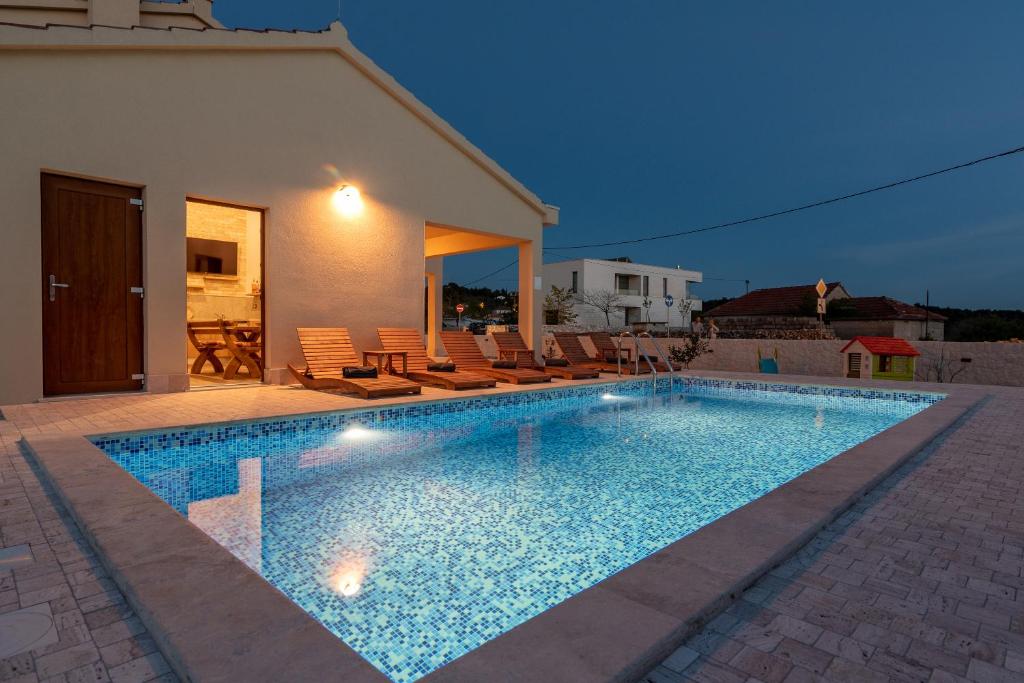 a swimming pool in front of a house at Vila Vanessa Trogir - Čiovo in Trogir