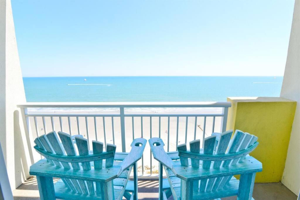 two blue chairs sitting on a balcony overlooking the ocean at Oceanfront TOP LOCATION MODERN RESORT Lazy River Huge Pool Oasis in Myrtle Beach