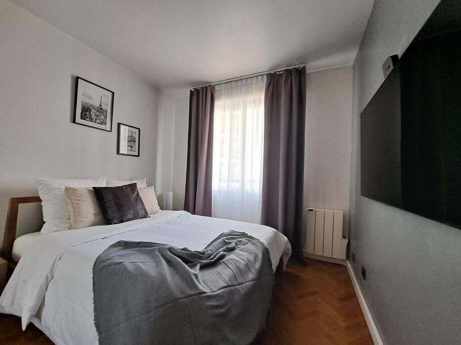 a bedroom with a large bed and a flat screen tv at Appartement aux Portes de Paris et 5 minutes du métro in Charenton-le-Pont