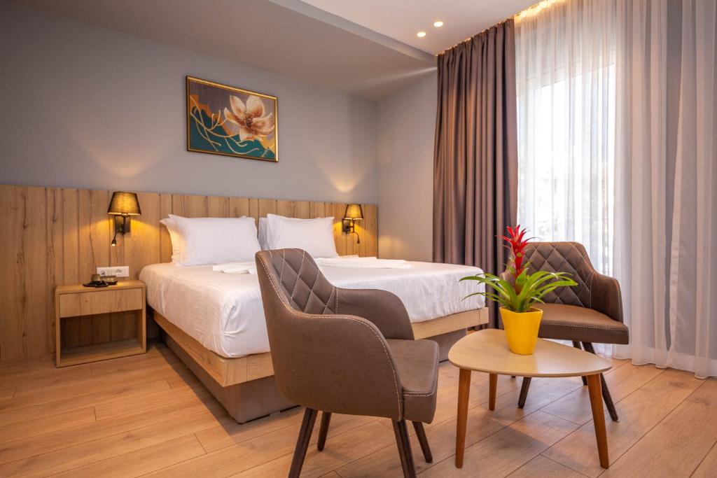 Habitación de hotel con cama, mesa y sillas en Azure Inn Hotel, en Sarandë
