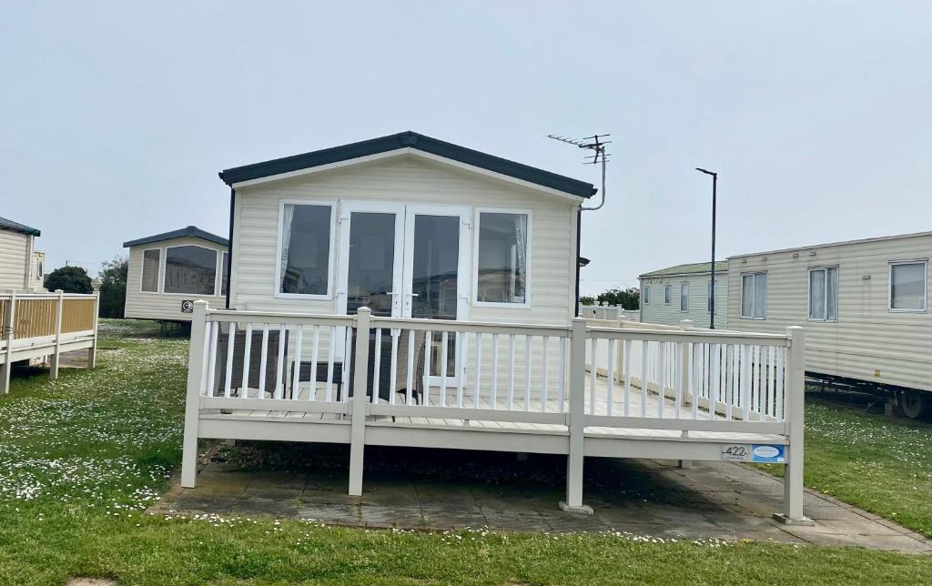 a small white house with a white porch at Cosy holiday home at Romney Sands in New Romney