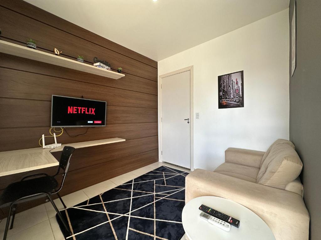 uma sala de estar com um sofá e uma televisão na parede em Flat aconchegante próximo a Pelinca em Campos dos Goytacazes