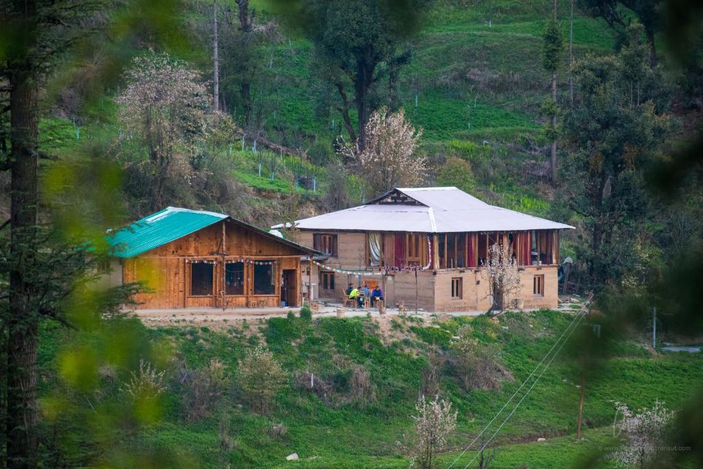 a wooden house with a blue roof on a hill at Mud Hostel Shangarh in Shangarh