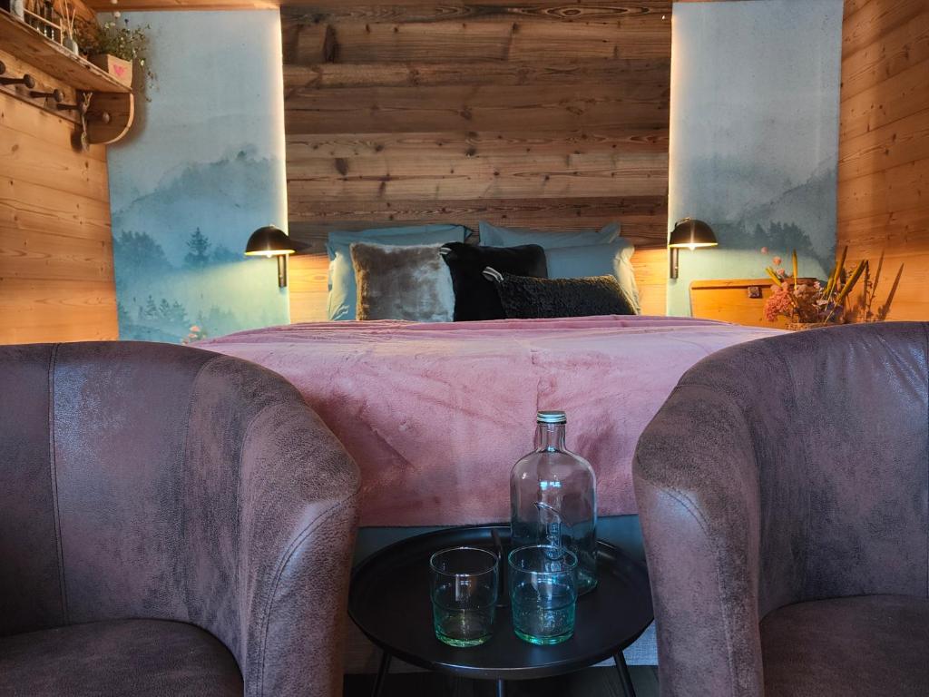 Schlafzimmer mit einem Bett mit 2 Stühlen und einer Flasche auf einem Tisch in der Unterkunft Chambre Trèfle in Entremont