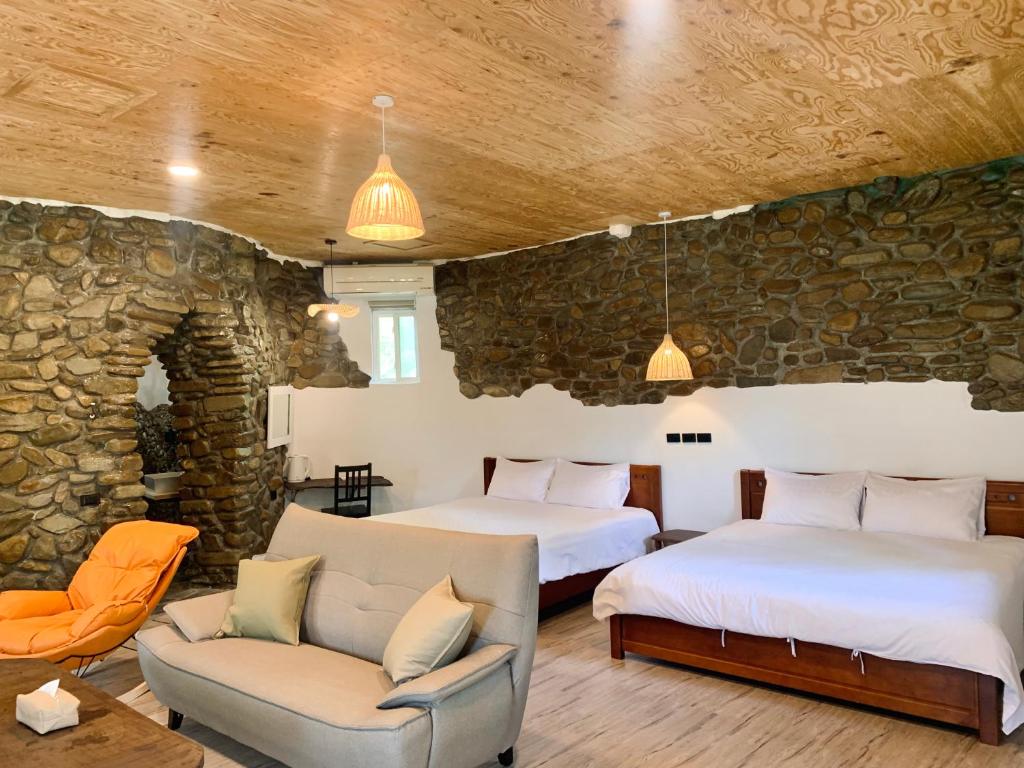 2 camas en una habitación con una pared de piedra en 滿丘石頭屋ManChill en Manzhou