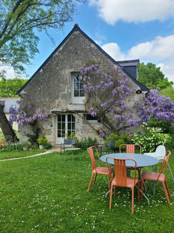 stół i krzesła przed domem z fioletowymi kwiatami w obiekcie Gîte de la bergerie w mieście Villandry