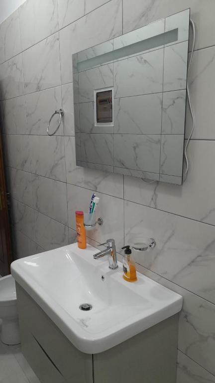 W białej łazience znajduje się umywalka i lustro. w obiekcie Luxury Dennis Home w Sarandzie