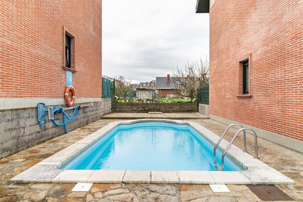 a swimming pool in front of a brick building at La Solana de Boo in Boó de Piélagos