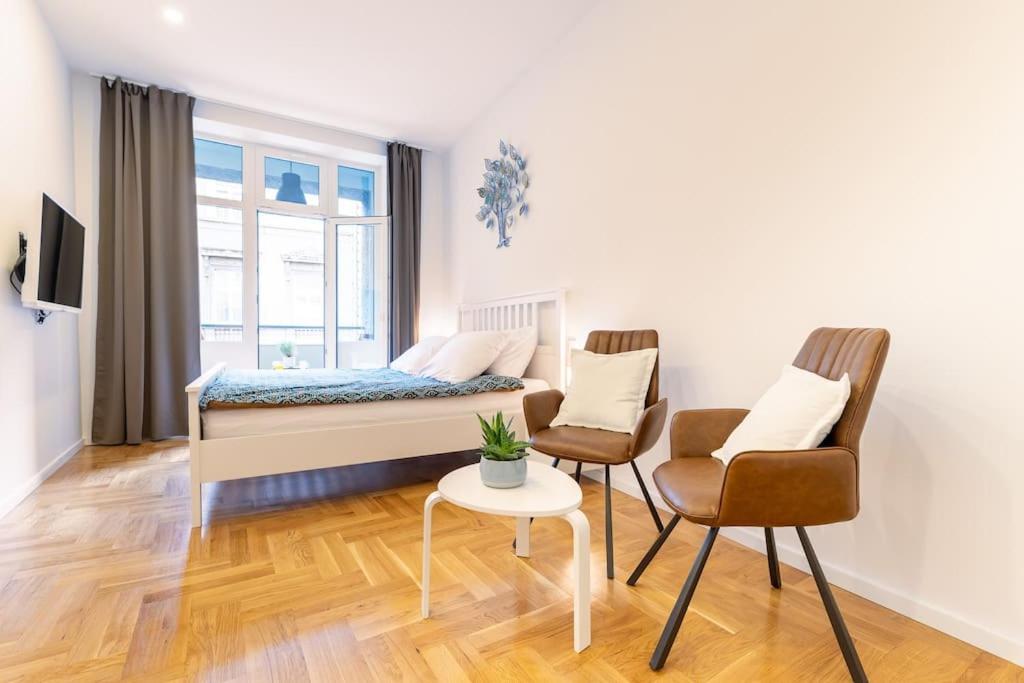 a bedroom with a bed and two chairs and a table at Petra - Official 4* One Bedroom Apartment-Balcony in Zagreb
