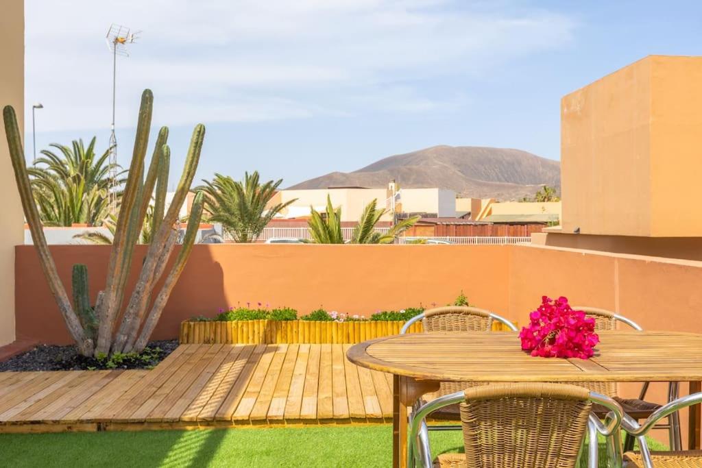 a wooden table and chairs on a patio with a table at Garden house with two terraces in Corralejo