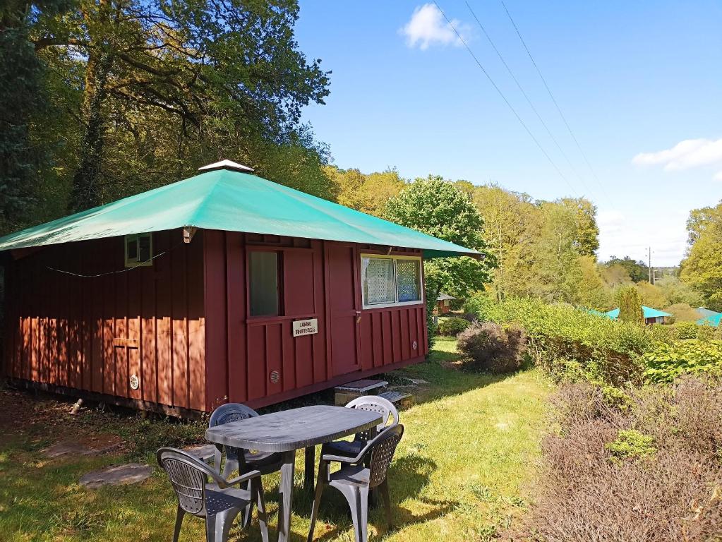 eine rote und grüne Hütte mit einem Tisch und Stühlen in der Unterkunft Les cabanes de l'île aux oiseaux Guern in Guern