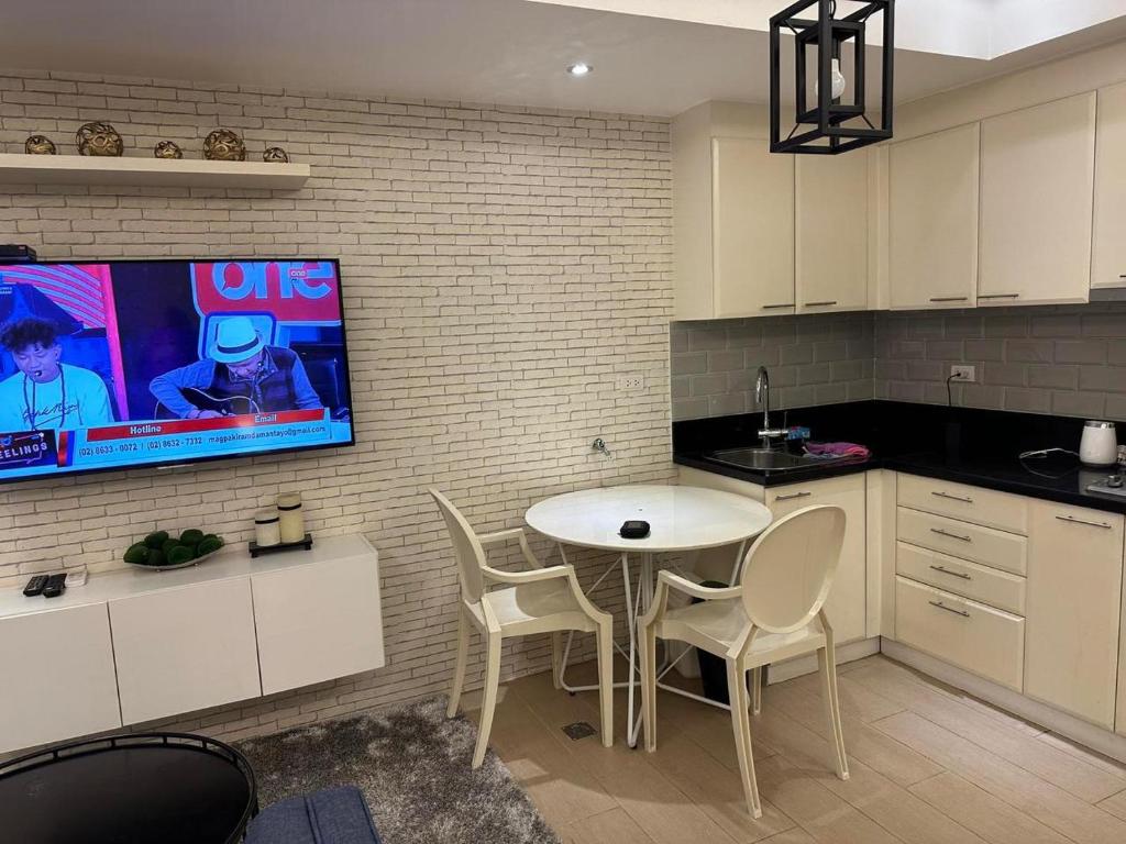 a kitchen with a table and chairs and a tv on a wall at The Pearl - Venice Luxury Residences McKinley in Manila