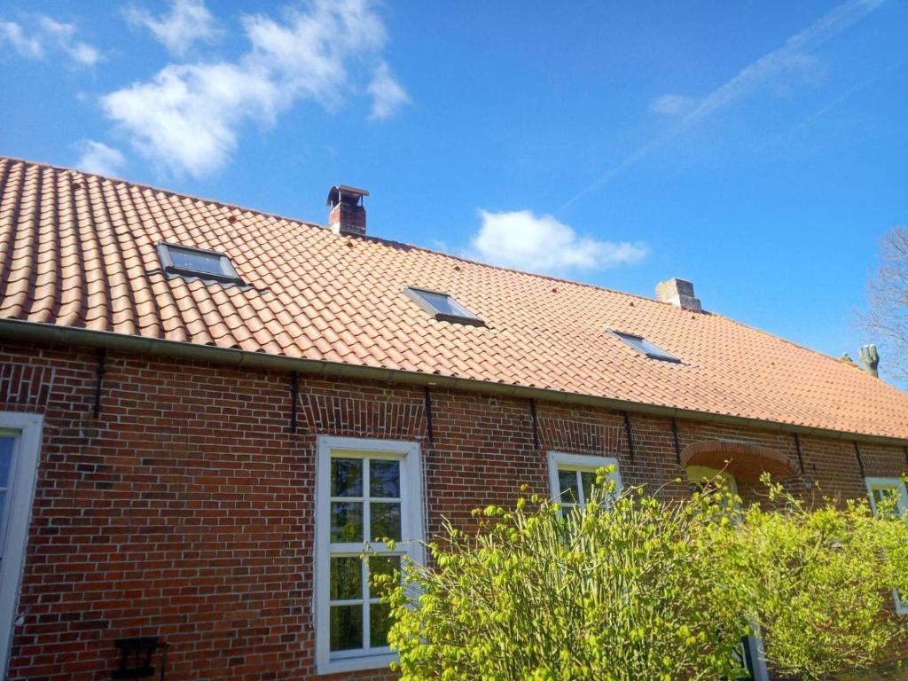 une maison en briques rouges avec un toit de galets dans l'établissement Alte Pastorei Jennelt, à Krummhörn