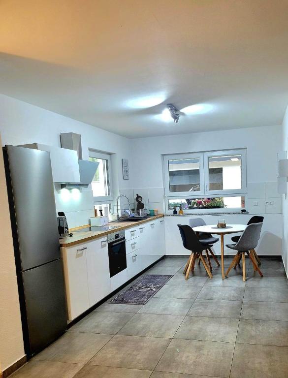 a kitchen with a refrigerator and a table with chairs at Ferienwohnung Hanek in Annweiler am Trifels