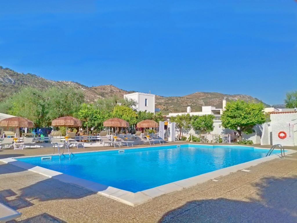 a large swimming pool with chairs and umbrellas at Hotel Residence Torre Del Porto in Mattinata