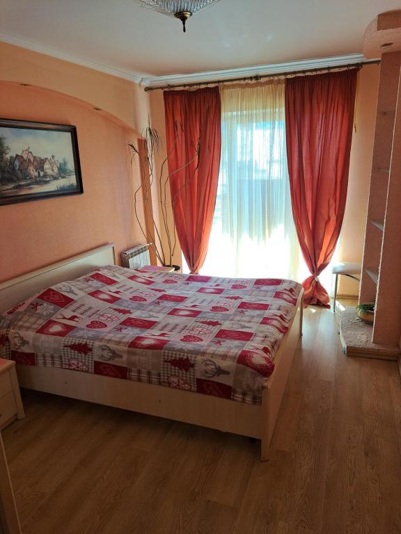 Schlafzimmer mit einem Bett und einem Fenster mit roten Vorhängen in der Unterkunft Квартира в центрі на Волі 8 in Luzk