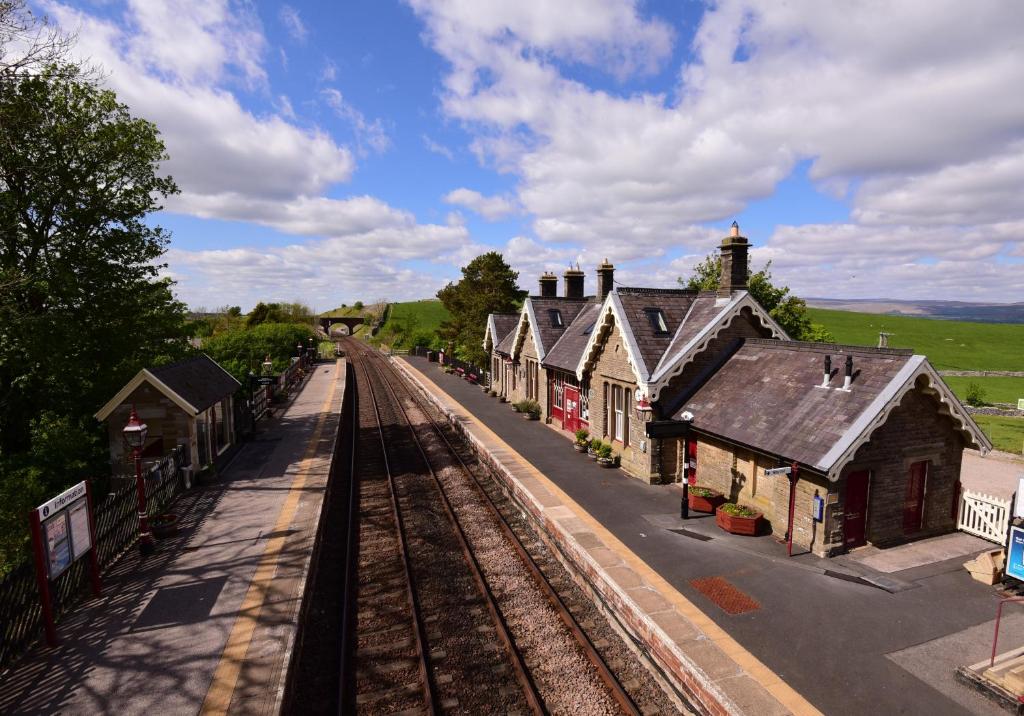 a train station with a train track and buildings at Station Cottage in Kirkby Stephen