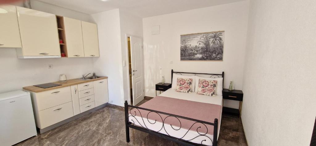 ein kleines Schlafzimmer mit einem Bett und einer Küche in der Unterkunft Apartments Petar Komiza in Komiža