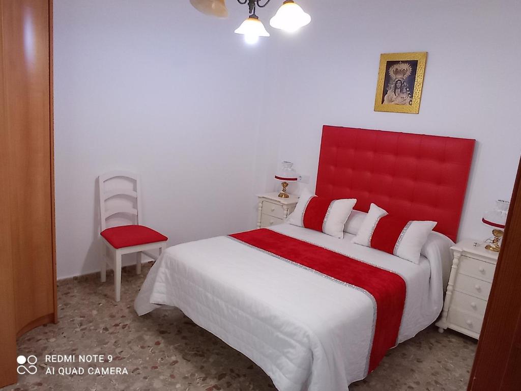 - une chambre avec un grand lit et une tête de lit rouge dans l'établissement habitación turquesa, à Barbate