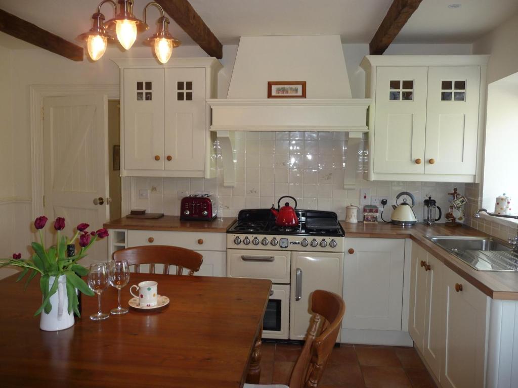 cocina con armarios blancos y mesa de madera en Hawthorn Cottage, en Greencastle