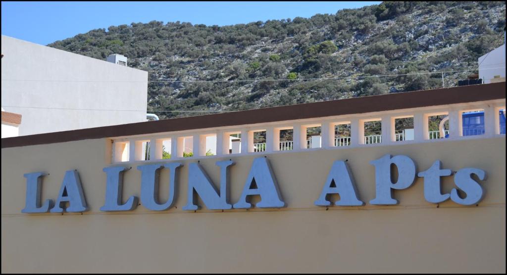 a sign on a building with a mountain in the background at La Luna Apartments in Stalida