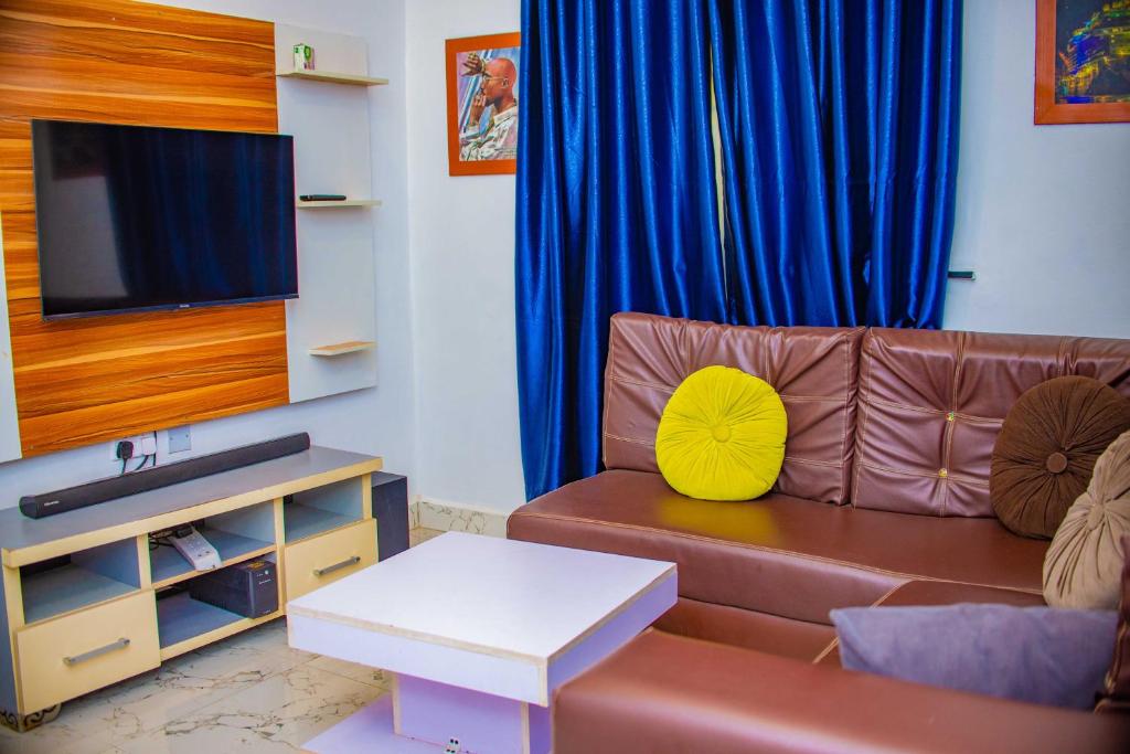 een woonkamer met een bruine bank en een tv bij Stylish 1-Bed-Apt With 24hrs Power + Fast Wi-Fi in Lagos