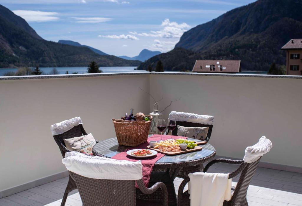 a table with a plate of food on a balcony at Attico con vista sul lago e montagne a Molveno in Molveno