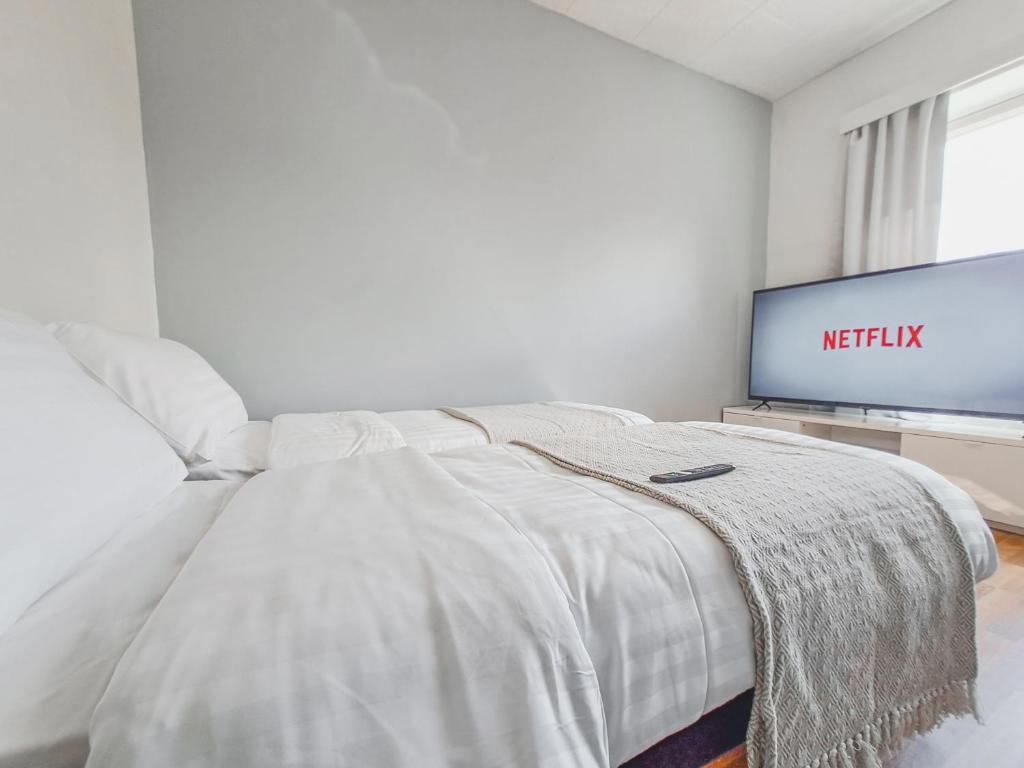 a white bedroom with a bed and a flat screen tv at Residential Homes Franzén in Helsinki