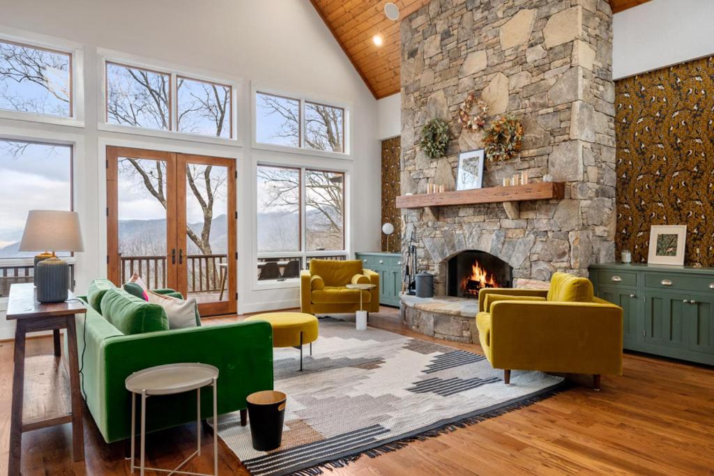 una sala de estar con muebles amarillos y verdes y una chimenea de piedra. en The Morningside Lodge in Bear Lake Reserve, en Tuckasegee