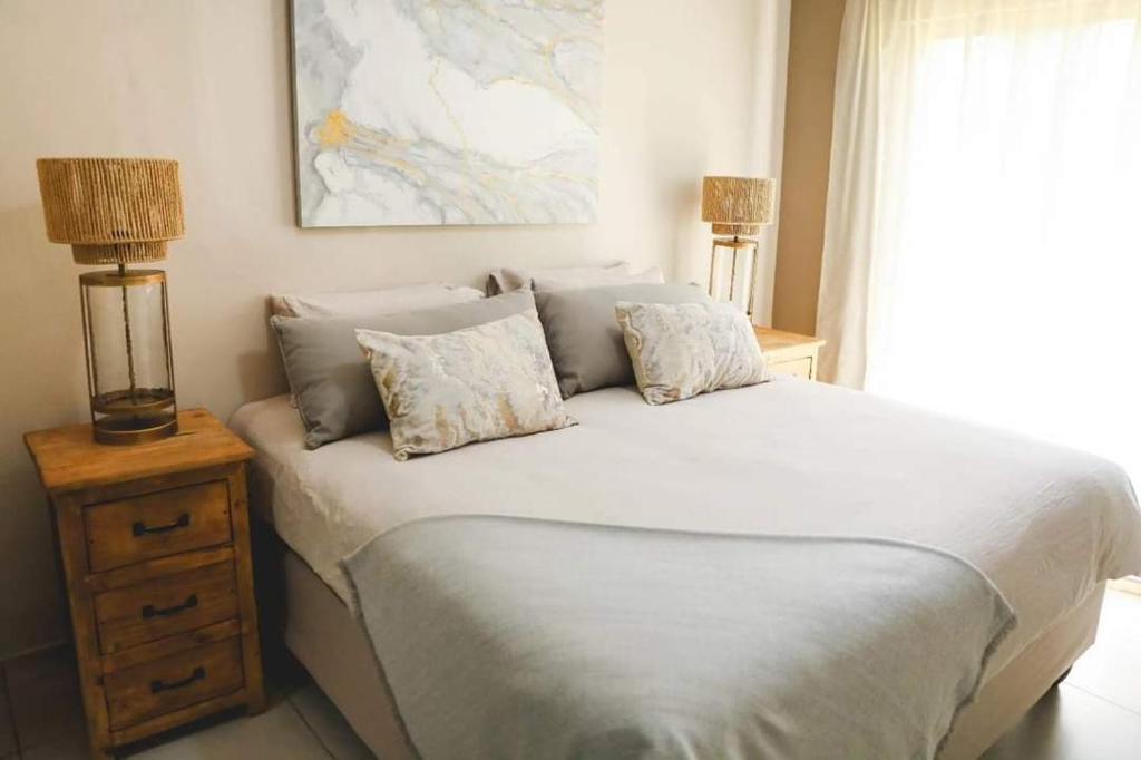 a bedroom with a large white bed with two lamps at Serendipity Boutique Guest house in Welkom