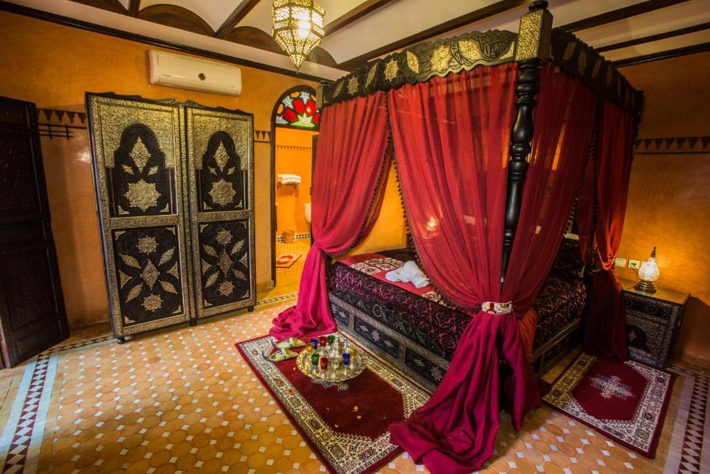a bedroom with a canopy bed with red curtains at Riad Ritaj in Meknès