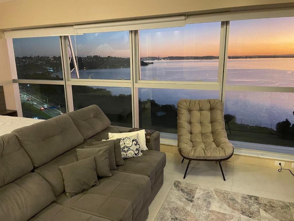 a living room with a couch and a chair at Loft com vista incrível no Barra Shopping in Porto Alegre